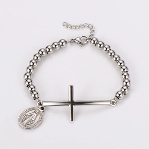 Detail of silver beaded bracelet featuring a large cross and religious oval pendant
