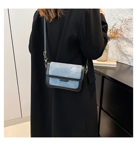 Detailed view of the adjustable black shoulder strap and hardware on the denim crossbody bag
