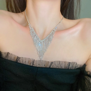 Close-up of a silver V-shaped tassel necklace with sparkling rhinestones on a model