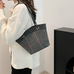 Canvas checkered bucket tote bag with red stripes and leather handle worn by model