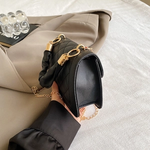 Detalle del bolso acolchado negro con asa fruncida y correa de cadena dorada elegante