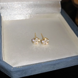 Macro de boucles d'oreilles fleurs dorées avec zircons blancs sur boîte à bijoux en velours
