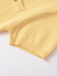 Detail of yellow knit cardigan showing button placket and vertical ribbed texture fabric
