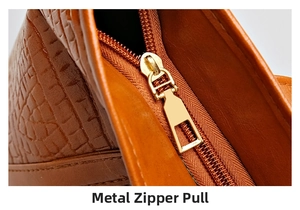 Detailed close-up of premium golden metal zipper pull on brown crocodile texture tote bag