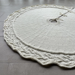 Macro view of cream knit Christmas tree skirt with intricate cable pattern and wavy edges