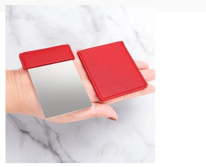 Detail of portable rectangular stainless steel mirror with red leather protective sleeve