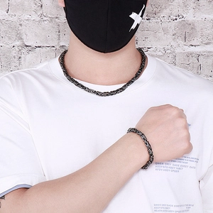 Dettaglio della collana e bracciale in acciaio nero e argento a forma di V stile hip hop