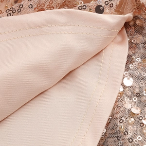 Close-up of sparkling rose gold sequins and precision stitching on the dress fabric