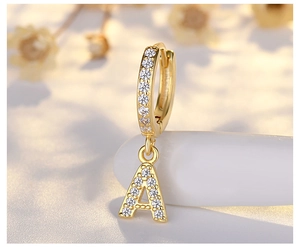Macro shot of gold-plated S925 silver earring with a sparkling diamond-set letter A charm