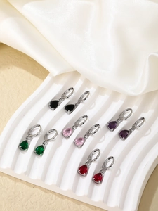 Detail view of pear-cut drop earrings in black, pink, purple, emerald, and red gems
