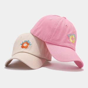 Pink and beige cotton baseball caps with STUDIO sunflower embroidery on a light background