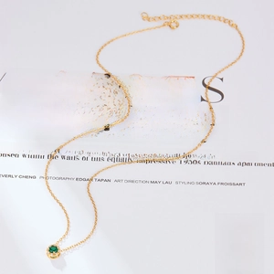 Detail of 925 sterling silver gold necklace with green zircon pendant on fashion background
