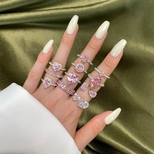 Detail of silver rings with pink teardrop and heart-shaped zircons on silk fabric