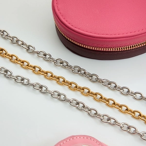 Detail of silver and gold plated stainless steel star pendant chains on a white surface