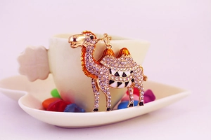 Detailed macro view of a golden camel keychain with crystal rhinestones on a white plate