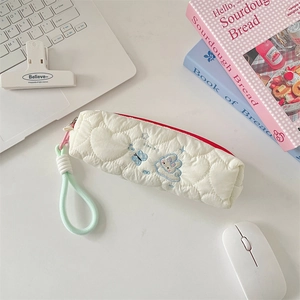 Detail of white quilted pencil case with rabbit embroidery and heart-shaped patterns