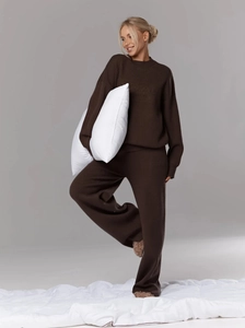 Detail view of pink knit lounge set featuring home aesthetics embossed logo and wide-leg pants
