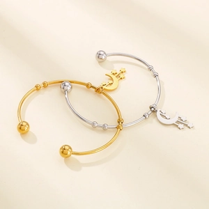 Detail of moon and star charms on gold and silver stainless steel open bangles