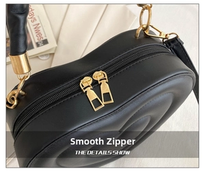 Details der herzförmigen schwarzen Ledertasche mit glatten goldenen Doppelreißverschlüssen