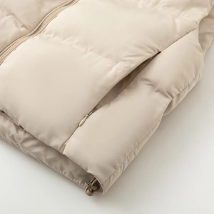 Detail of invisible zipper pocket and adjustable drawstring hem on beige quilted vest
