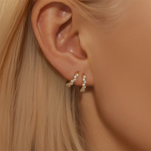 Close-up of elegant gold S925 sterling silver hoop earrings with pavé set crystals on a model