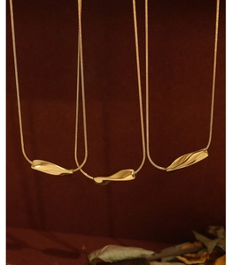 Detail of three twisted gold bar pendants on delicate snake chains with retro aesthetic