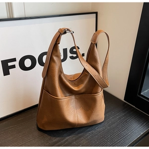 Detail showing brown hobo bucket bag with two front pockets on a dark wood surface