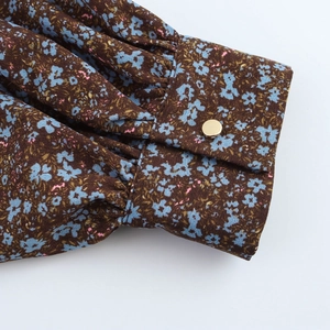 Floral chiffon dress sleeve detail featuring a gold button and delicate lace patchwork