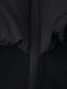 Detailed macro view of the black jacket hem showing stitching and mixed fabric texture
