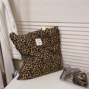 Detail shot of leopard print tote bag with woven label on a rustic white wood background
