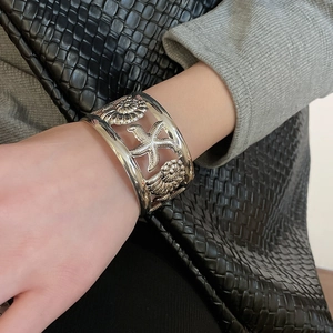 Close-up of a textured silver cuff bracelet with embossed starfish and seashell details