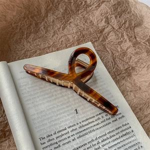 Detail of tortoise shell acetate hair claw clip with gold spring on a vintage book