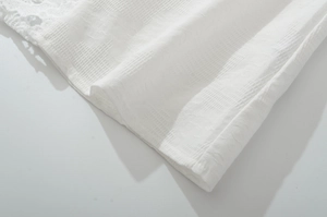 Detailed macro view of white textured woven fabric with delicate lace拼接 and hem stitching