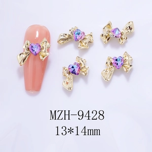Detail of golden bow nail art charms with purple heart rhinestones, 13x14mm size charms