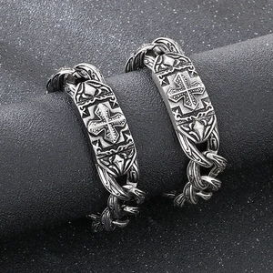 Macro view of vintage stainless steel chain bracelets with embossed cross plate detail