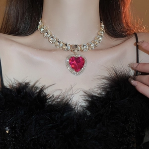 Close-up of gold necklace with rose red heart crystal and rhinestone chain on a model