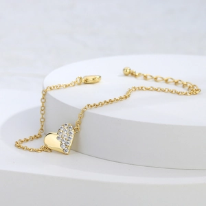 Elegant gold plated heart bracelet with sparkling cubic zirconia on a white display stand