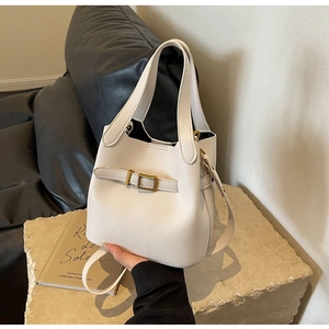 Detailed macro view of white lychee pattern leather texture and gold buckle on bucket bag