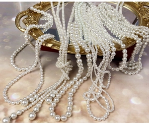Detailed close-up of multiple sizes of baroque pearl necklaces on a vintage gold frame