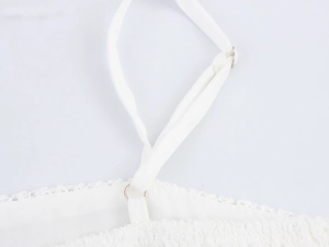 Close-up of adjustable spaghetti strap with metal buckle on a white lace mesh dress