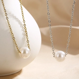 Detail von Gold- und Silberhalsketten mit weißer Perle auf seidigem beigem Stoff
