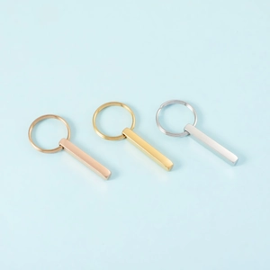 Minimalist stainless steel bar keychains in gold, rose gold, and silver on blue background