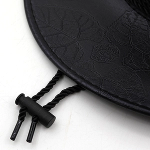 Detail eines schwarzen Leder-Cowboyhutes mit Blattprägung und verstellbarem Kinnriemen