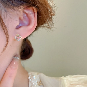 Close-up of a gold-plated four-leaf clover earring with sparkling zircon on a model