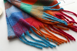 Macro detail of soft colorful plaid scarf with fuzzy texture and long fringed tassels