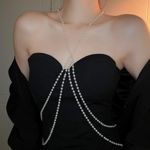 Detailed view of multilayer pearl body chain with golden rings on black garment