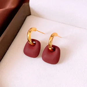 Matte wine red trapezoidal earrings with gold curved hooks in a velvet box