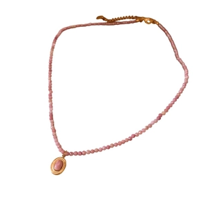Pink rhodochrosite beaded necklace with a gold oval pendant and pink gemstone focal