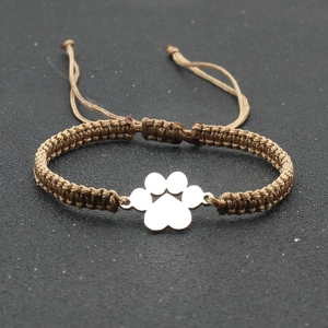 Detail view of woven brown cord bracelet with silver dog paw charm and adjustable knot