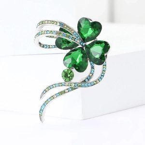 Macro detail of elegant silver clover brooch with green heart crystals and rhinestones
